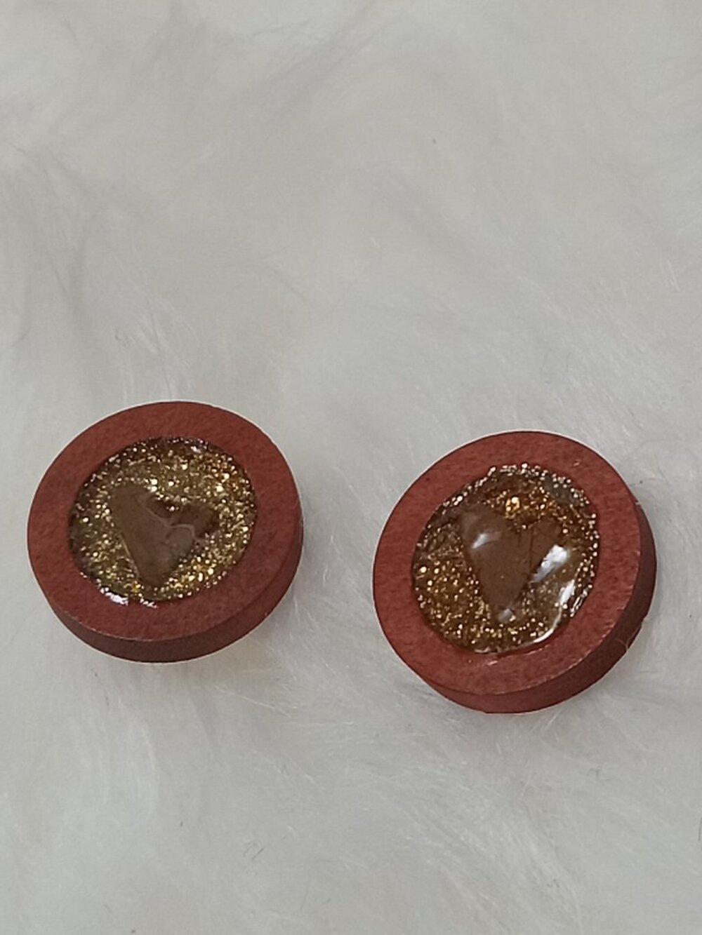 Handmade earrings on a wooden base with a piece of punched-out tree leaf